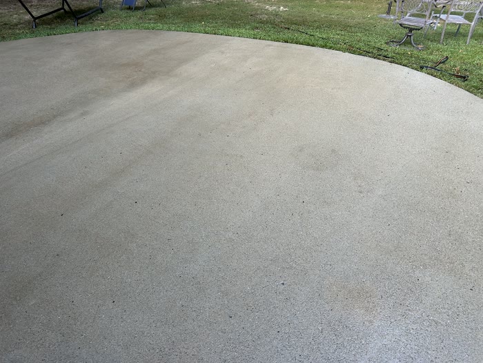 Clean concrete patio running out to the lawn, with patio chairs at its far edge.